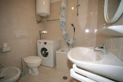 a bathroom with a sink and a toilet and a washing machine at Residence Roacia in Alba di Canazei