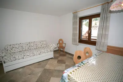 a living room with a couch and a bed and a window at Residence Roacia in Alba di Canazei