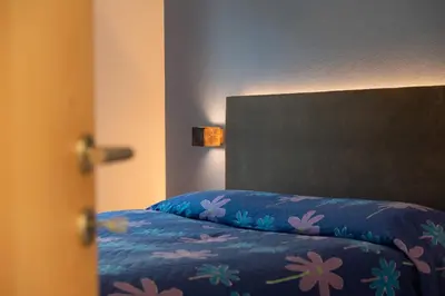 a bed with a blue blanket with flowers on it at Appartement Marlene in Appiano sulla Strada del Vino