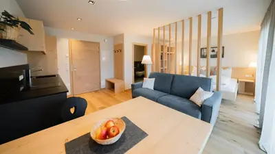 a living room with a table and a blue couch at Oberzerod Apartments in Siusi