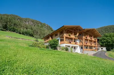 a house on the side of a hill with a green field at Oberzerod Apartments in Siusi