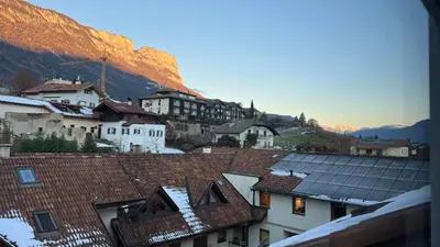 a group of buildings and roofs with mountains in the background at NEW Suite mar e monti in Appiano sulla Strada del Vino