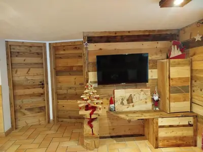 a living room with wooden walls and a flat screen tv at Botton d'oro in Campitello di Fassa