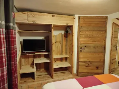a bedroom with a tv and a wooden closet at Botton d'oro in Campitello di Fassa