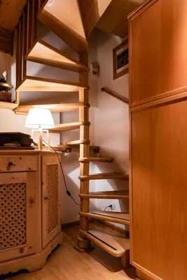 a spiral staircase in a room with a lamp at SciliarGuestHouse-due piani parcheggio privato in Castelrotto