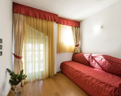 a living room with a red couch and a window at Romantic Charming Hotel Rancolin in Moena