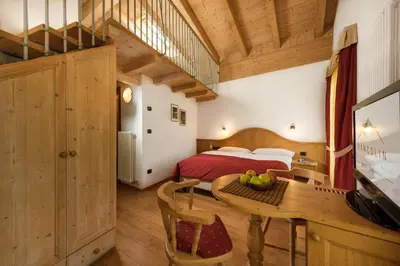 a bedroom with a bed and a table in a room at Romantic Charming Hotel Rancolin in Moena