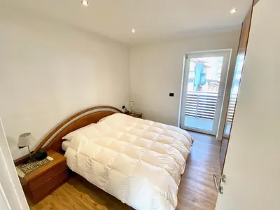 a bedroom with a white bed and a wooden floor at Villa Dada in Predazzo