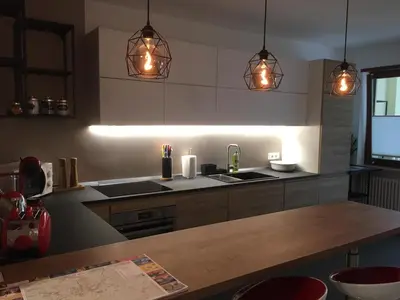 a kitchen with three pendant lights and a wooden table at LaSiesta Merano in Merano