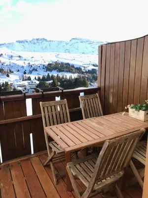 a wooden table and chairs on a deck with a view at Appartamento con vista sull'Alpe di Siusi in Bulla