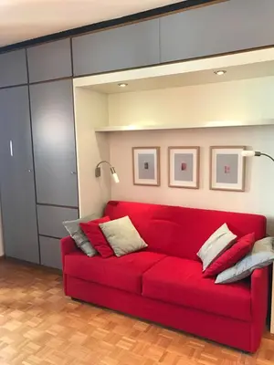 a red couch sitting in a living room at Appartamento con vista sull'Alpe di Siusi in Bulla