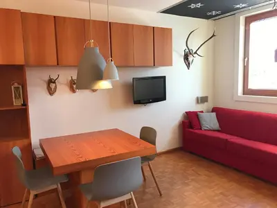 a living room with a table and a red couch at Appartamento con vista sull'Alpe di Siusi in Bulla