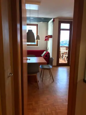 a living room with a table and a red couch at Appartamento con vista sull'Alpe di Siusi in Bulla