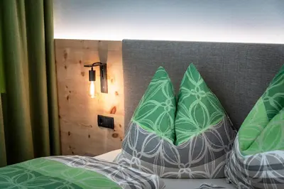 a bed with green and white pillows on it at Mesnerhof in Valles