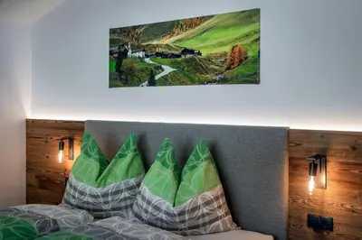 a bed with pillows and a picture on the wall at Mesnerhof in Valles