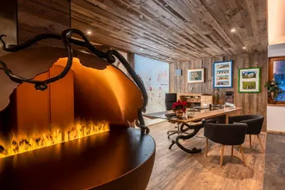 an office with a fireplace in the middle of a room at Hotel Majon Miramonti in Canazei