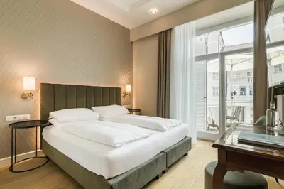 a white living room with a tv on a white table at Hotel Europa Splendid in Merano