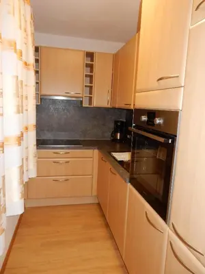 a kitchen with wooden cabinets and a black appliance at La Pineta in Colfosco