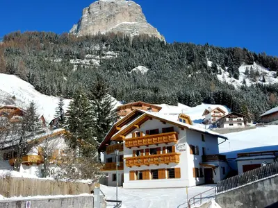 a building in the snow with a mountain in the background at La Pineta in Colfosco