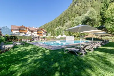 a living room with a couch and a television at Hotel La Maison Wellness & Spa in Alleghe