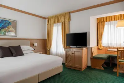 a bedroom with a large white bed and a couch at Hotel La Maison Wellness & Spa in Alleghe