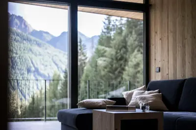 a living room with a blue couch and a large window at Stelza Nature Chalet in Val di Vizze