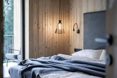 a bedroom with a bed and a lamp and a window at Stelza Nature Chalet in Val di Vizze