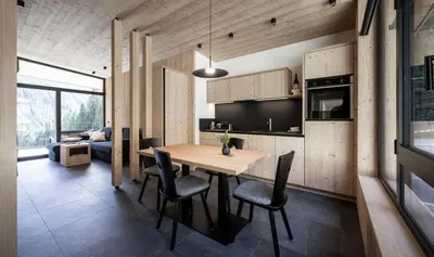 a kitchen and dining room with a wooden table and chairs at Stelza Nature Chalet in Val di Vizze