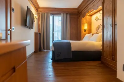 a hotel room with a bed and a chair at Faloria Mountain Spa Resort in Cortina dʼAmpezzo