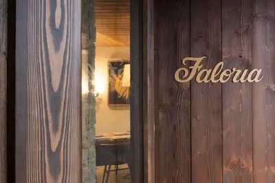 a table with a plate of food and glasses of wine at Faloria Mountain Spa Resort in Cortina dʼAmpezzo