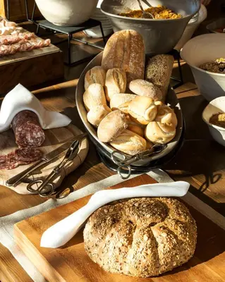 a table topped with plates of bread and fruit at Faloria Mountain Spa Resort in Cortina dʼAmpezzo