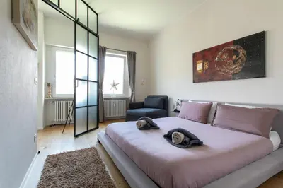 a bedroom with a large bed and a chair at Dolomiti 65 mq new flat in the center of Bolzano in Bolzano
