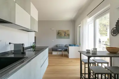 a kitchen with a counter and a table with stools at Dolomiti 65 mq new flat in the center of Bolzano in Bolzano