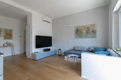 a living room with a blue couch and a tv at Dolomiti 65 mq new flat in the center of Bolzano in Bolzano