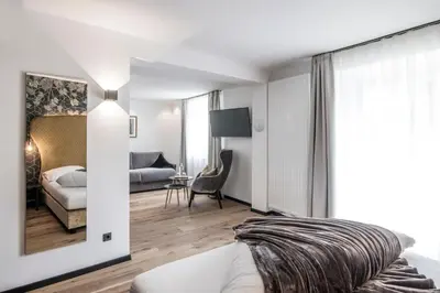 a bedroom with a bed and a living room at B&B Zur Traube in Vipiteno