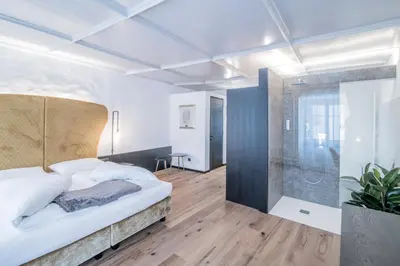 a bedroom with a large bed and a shower at B&B Zur Traube in Vipiteno