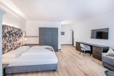 a bedroom with a bed and a desk and a television at B&B Zur Traube in Vipiteno