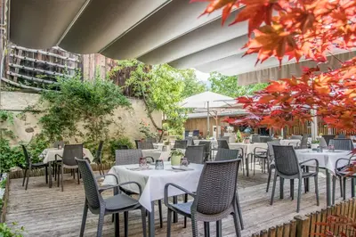 a restaurant with tables and chairs on a wooden deck at B&B Zur Traube in Vipiteno