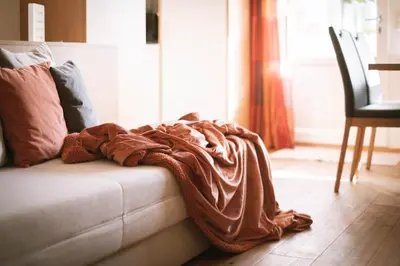 a blanket laying on a couch in a living room at dolomites view apartment in Rasun di Sopra