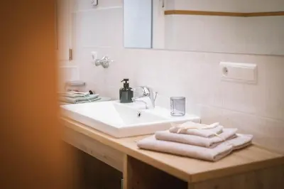 a bathroom sink with towels on a wooden counter at dolomites view apartment in Rasun di Sopra