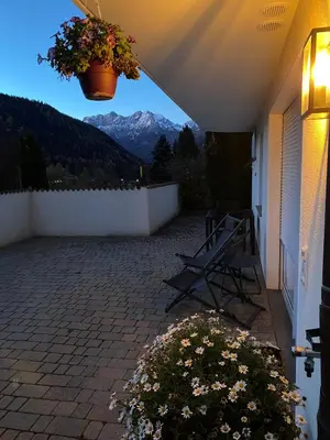 a patio with a bench and a view of mountains at dolomites view apartment in Rasun di Sopra