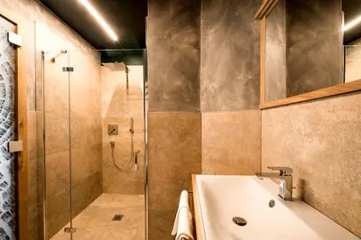 a bathroom with a shower and a sink and a tub at KRONE eat drink stay in Bressanone