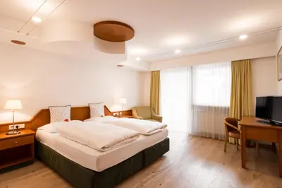a hotel room with a large bed and a desk at KRONE eat drink stay in Bressanone