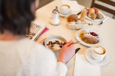 a woman sitting at a table with a plate of breakfast foods at KRONE eat drink stay in Bressanone