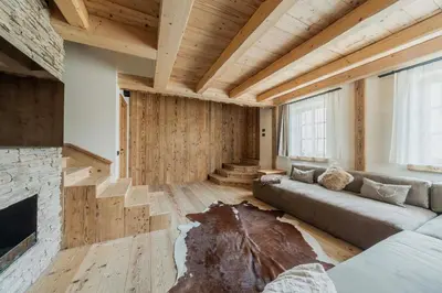 a living room with wooden stairs and a stone fireplace at Chalet Socrepes - Dolomiti Skyline in Cortina dʼAmpezzo