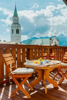 a wooden table and two chairs on a deck at Royal Hotel Cortina in Cortina dʼAmpezzo