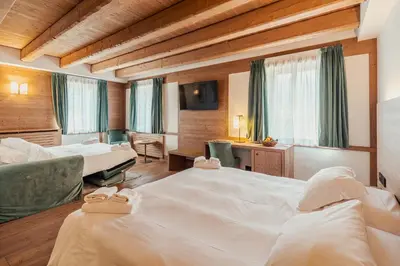 a hotel room with two beds and a desk at Royal Hotel Cortina in Cortina dʼAmpezzo