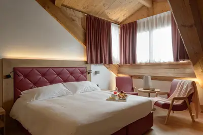 a bedroom with a large bed and two chairs at Royal Hotel Cortina in Cortina dʼAmpezzo