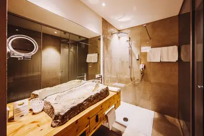 a bathroom with a shower and a bed and a sink at Gourmet - Boutique Hotel Tanzer in Falzes