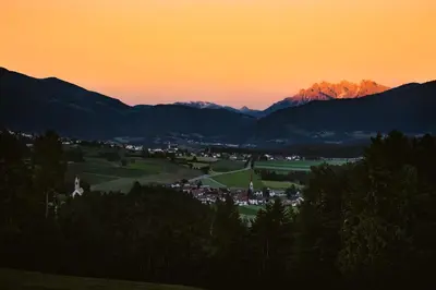 a sunset over a town with mountains in the background at Gourmet - Boutique Hotel Tanzer in Falzes